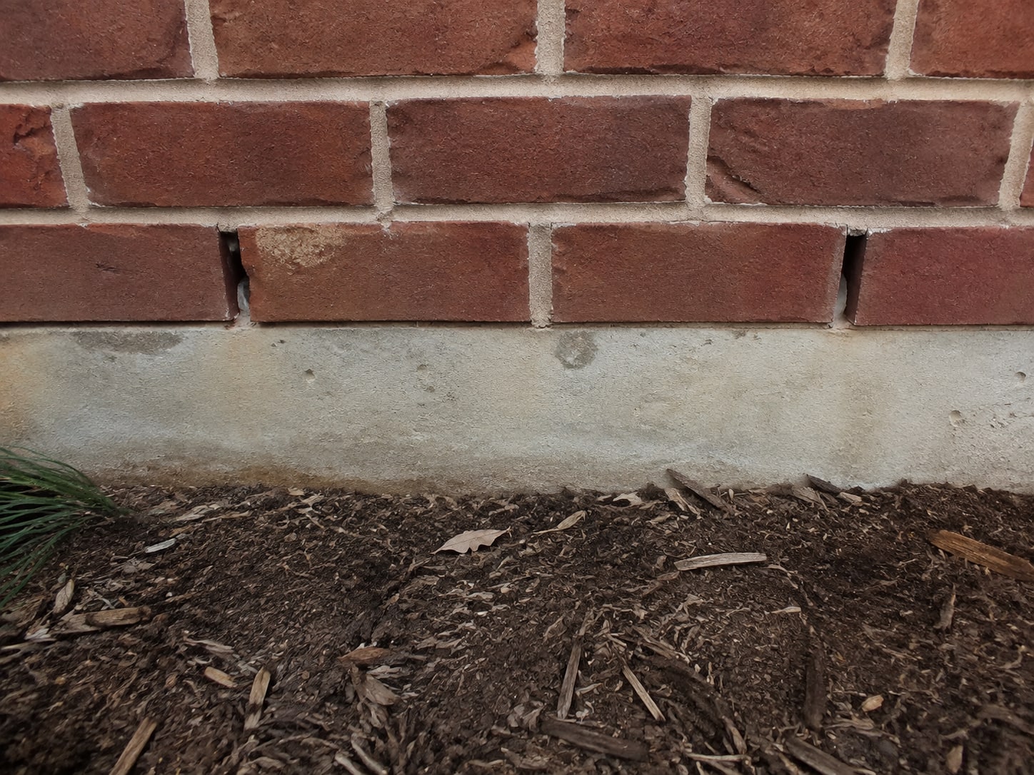 Open drainage joints at the base of the masonry accent.